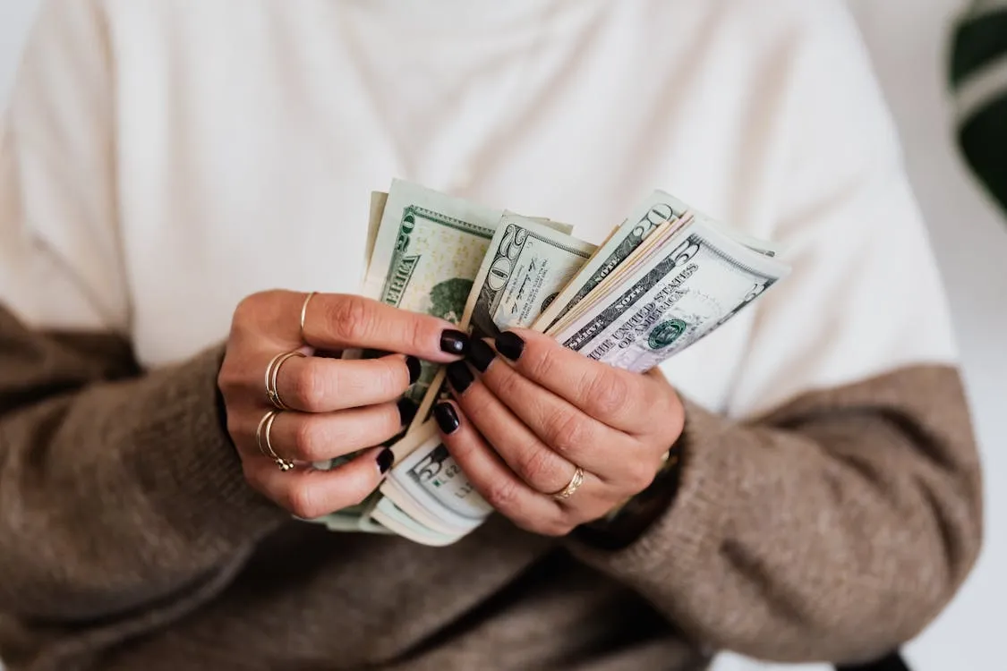 A close-up of a woman counting dollar bills